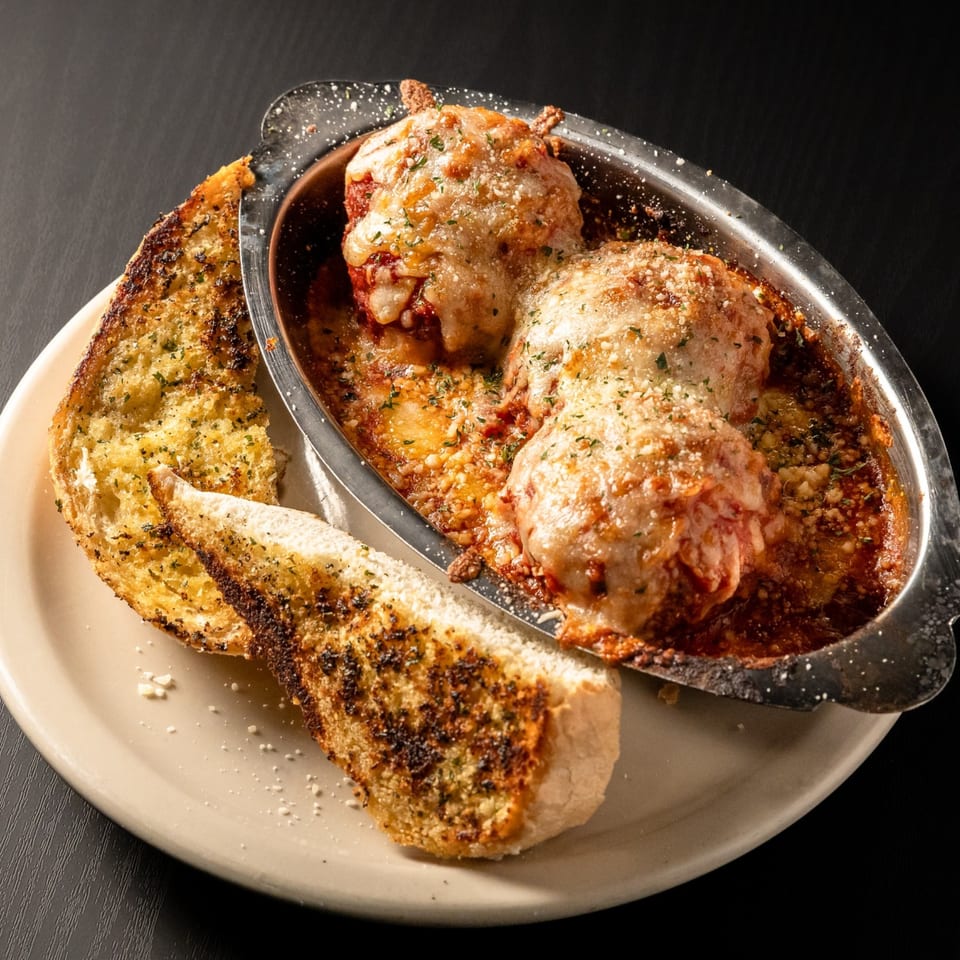 San Marino's baked meatballs in marinara sauce with melted cheese and two slices of garlic bread.
