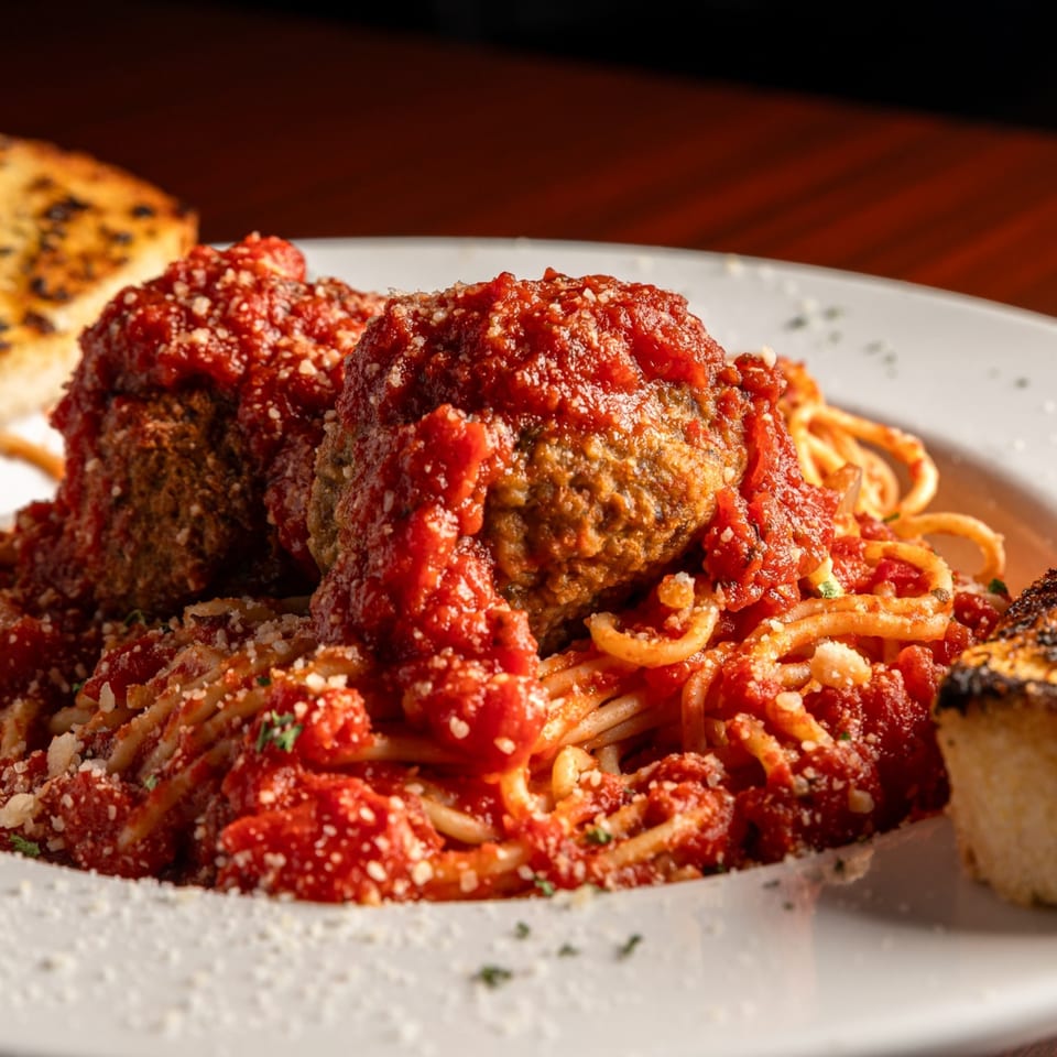 Spaghetti with two large meatballs, rich red marinara sauce, grated cheese, and toasted garlic bread.